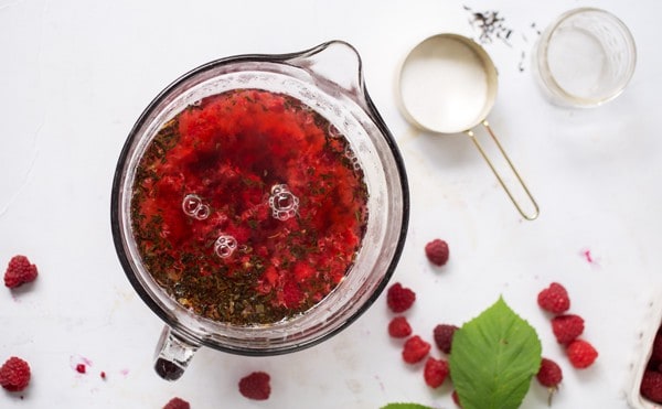 Fresh juicy berries infused into sweet black tea make beautiful jewel toned tea that combined with a splash of cream turn into a light pink Raspberry Infused Iced Black Tea Latte that is full of flavor and super refreshing! Iced Tea Recipe | Fruit Infused Iced Tea | Raspberry Tea | Real Fruit Flavored Tea #icedtea #raspberry #tealatte