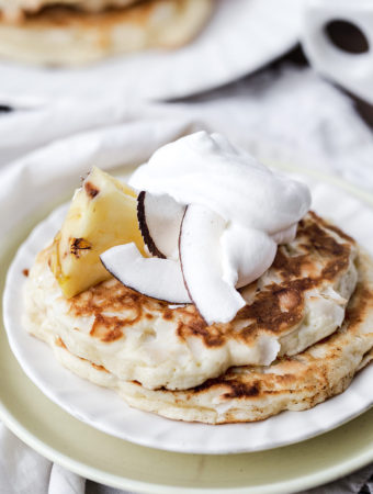 a stack of fresh pancakes topped with whipped cream and pinepple