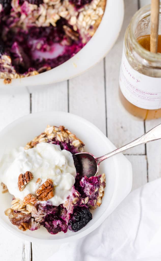 Scoop of blackberry baked oatmeal with greek yogurt and honey on the table